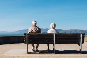 Elderly man and woman sitting on a bench.